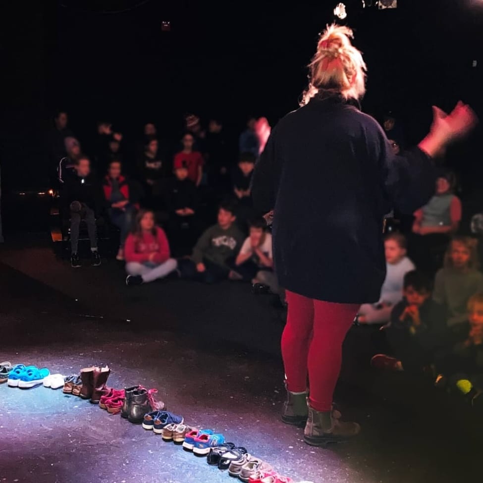 woman on stage with shoes behind her